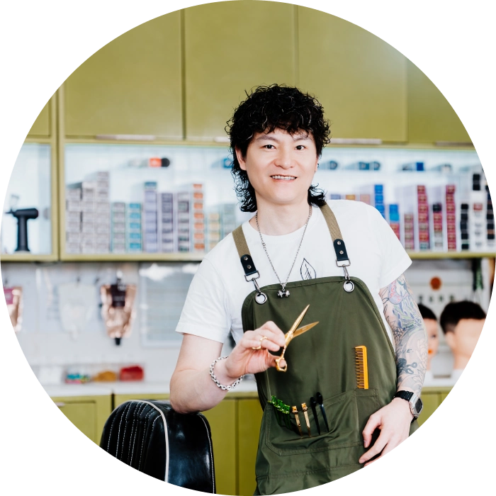 Barber in green apron smiling