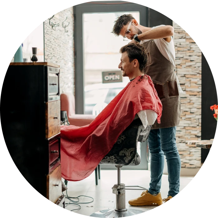 Hairdresser styling man in red cape